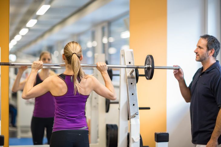 Eine Frau im Fitnesscenter mit einem Physiotherapeuten