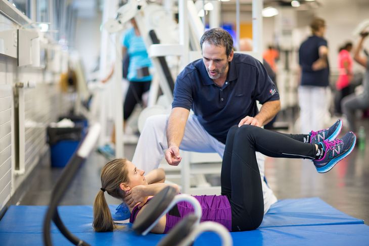 Der Physiotherapeut kontrolliert die Bewegungen einer Frau im Training